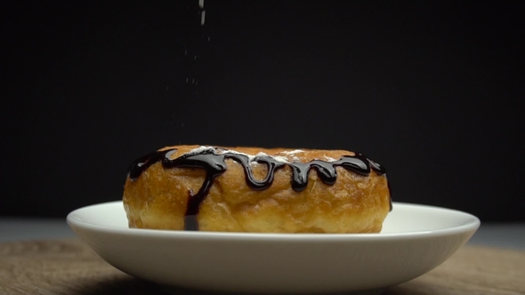 Delicious Sweet Donut Rotating on a Plate. Pouring by Sugar Powder