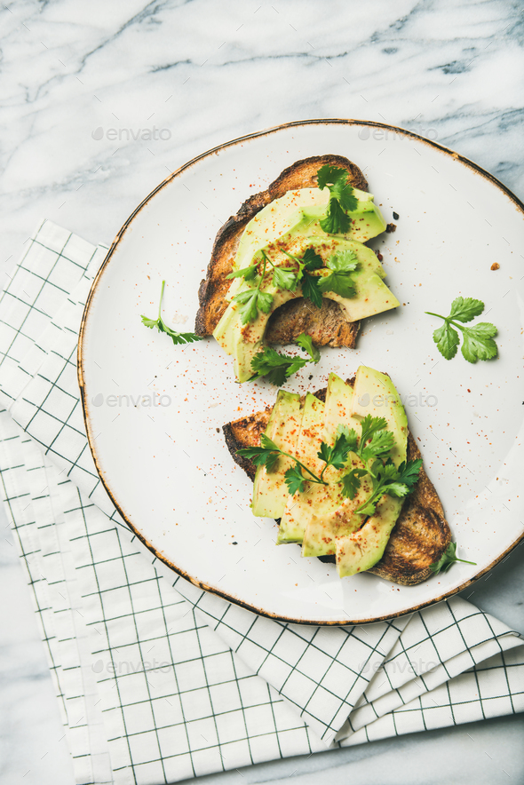 Flat-lay of avocado toast on plate over marble background - Stock Photo - Images