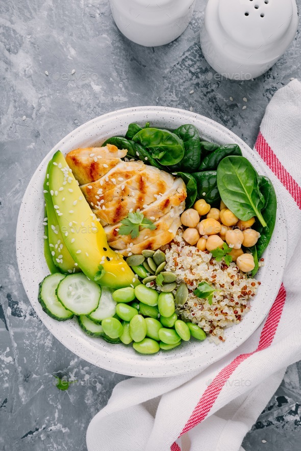 Buddha bowl with spinach, quinoa, chickpeas, grilled chicken, avocado, edamame beans, cucumbers - Stock Photo - Images