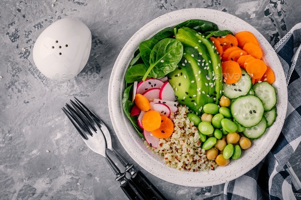 Vegan Buddha bowl with spinach, quinoa, chickpeas, avocado, edamame, cucumbers, carrots and sesame - Stock Photo - Images