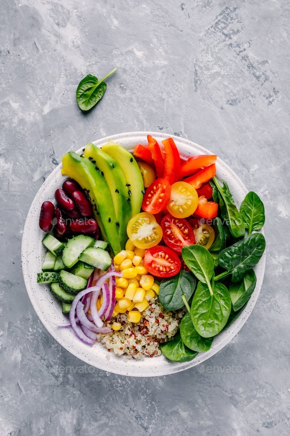 Buddha bowl. Avocado, quinoa, tomato, cucumber, red beans, spinach, red onion and red paprika Stock Photo by nblxer