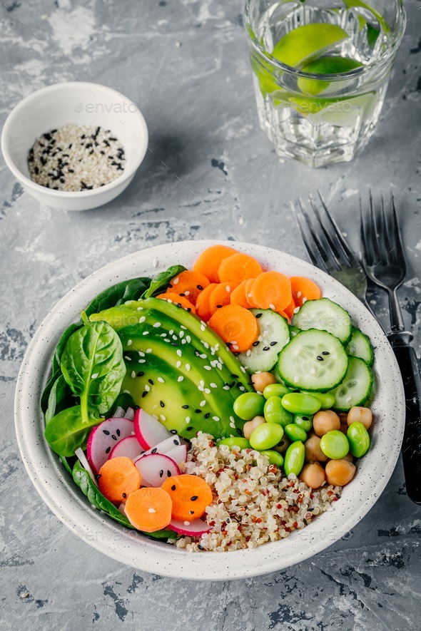 Vegan Buddha bowl with spinach, quinoa, chickpeas, avocado, edamame, cucumbers, carrots, radish - Stock Photo - Images