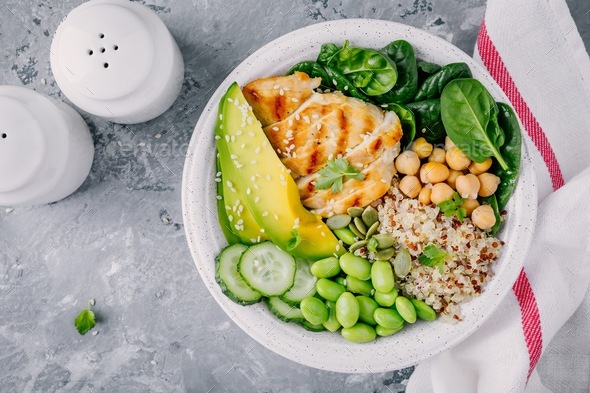 Buddha bowl with spinach, quinoa, chickpeas, chicken, avocado, edamame beans, cucumbers, sesame. - Stock Photo - Images