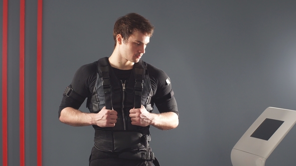 EMS, Portrait of Young Man Near Electro Muscle Stimulation Machine. alt