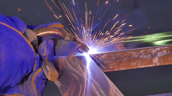 Metal Welding with Sparks and Smoke. Worker with Protective Mask Welding Metal. Welder Joins Metal alt