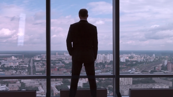 Full Length Back View of Successful Businessman in Suit Standing in Office with Hands on Waist, CEO alt