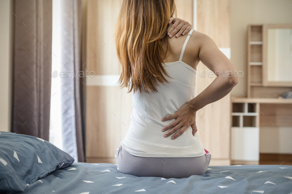Woman suffering from back ache on the bed - Stock Photo - Images