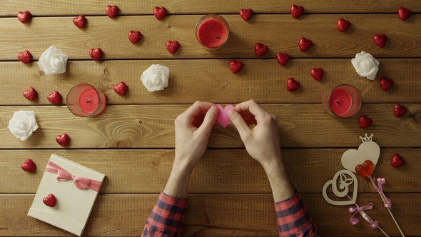Cheerful Man with Paper Heart Sits By Wooden Table, Top View