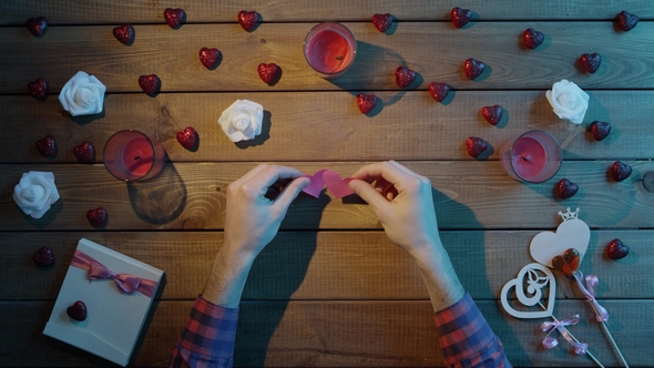 Adult Man with Handmade Paper Hearts Sits By Wooden Table, Top View