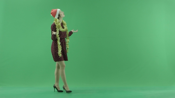 A Young Christmas Woman Is Going From the Left Side Under the Snowfall on the Green Screen
