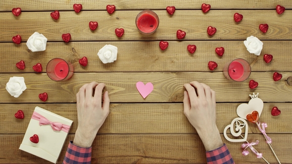 Man with Handmade Hearts of Paper Sits By Table, Top View