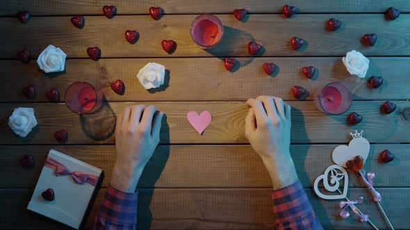 Adult Man with Handmade Hearts of Paper Sits By Table, Top View