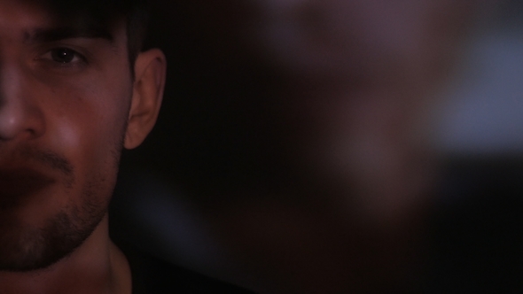 of a Male's Gray Eye Watching a Video or Film on TV or a Computer Monitor. Reflection on His Face alt