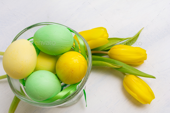 Easter table centerpiece with yellow tulips and painted eggs in - Stock Photo - Images