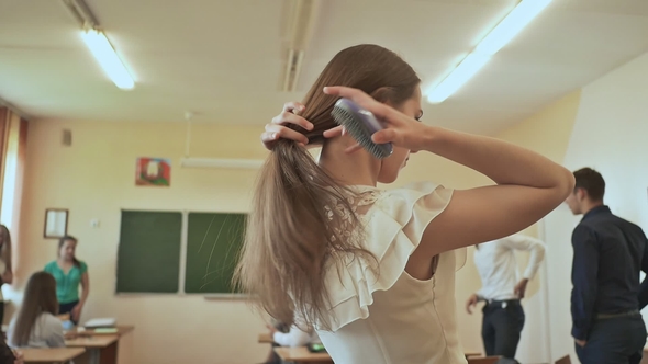 A Young Student Combs Her Hair Between Lessons in the Classroom. Russian School. alt