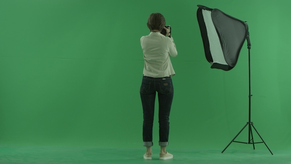 A Young Woman Taking Photos on the Side Back To the Viewer on the Green Screen