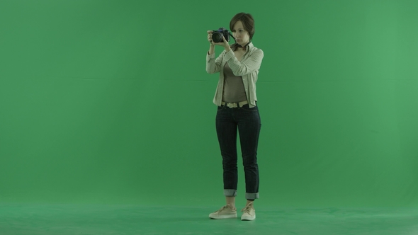 A Young Woman Is Tuning Her Camera on the Green Screen