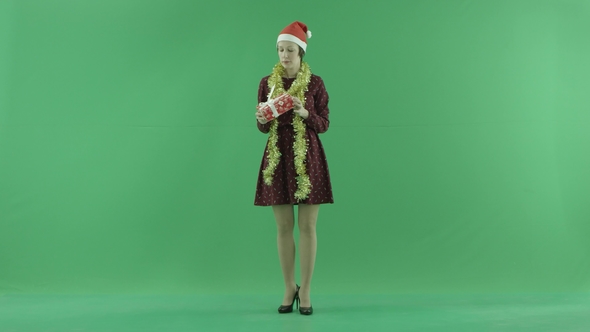 A Young Woman Is Looking for a Christmas Gift and Throwing It Up on the Green Screen