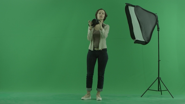 A Young Woman Taking Photos of a Viewer on the Green Screen and Correct His Standing
