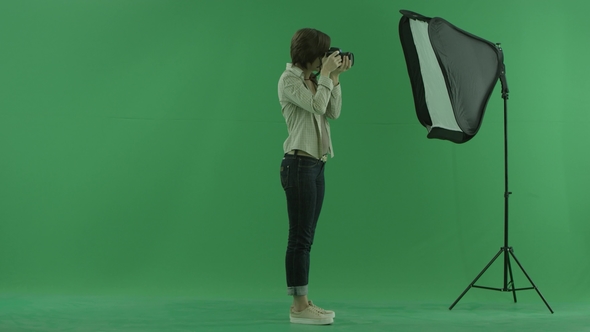 A Young Woman Taking Photos on the Right Hand Side on the Green Screen