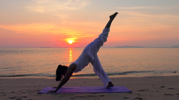 Asian Woman Practicing Yoga at the Sunset Sea