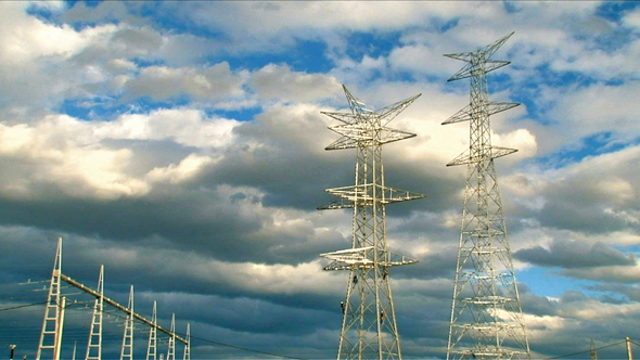 Electrical Towers with Workers and Clouds Crossing