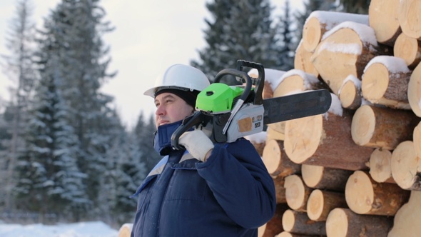 Worker With Chain Saw Against Pile of Logs