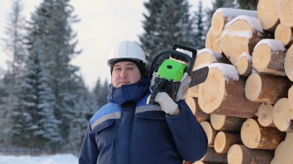 Worker With Chain Saw Against Pile of Logs