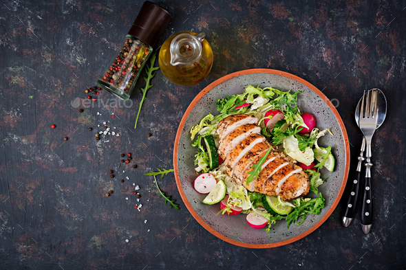 Bowl with salad of fresh vegetables and baked chicken breast on a dark background. - Stock Photo - Images