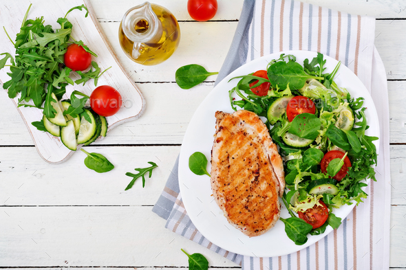 Grilled chicken breast and fresh vegetable salad - tomatoes, cucumbers and lettuce leaves. - Stock Photo - Images