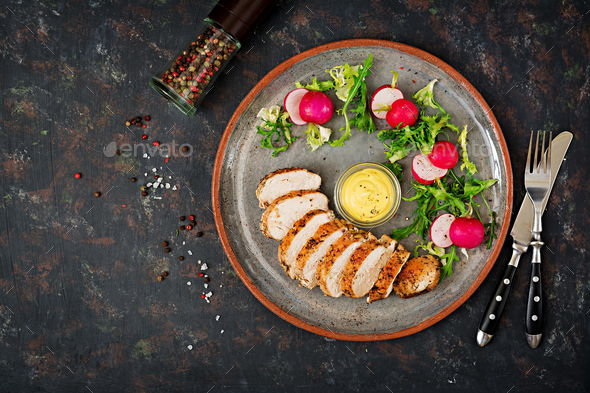 Baked chicken breast and fresh vegetables on the plate on a dark background. - Stock Photo - Images
