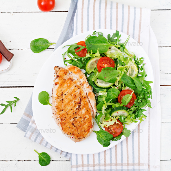 Grilled chicken breast and fresh vegetable salad - tomatoes, cucumbers and lettuce leaves. - Stock Photo - Images