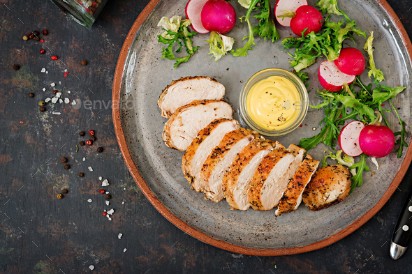Baked chicken breast and fresh vegetables on the plate on a dark background. - Stock Photo - Images