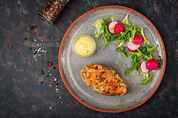 Baked chicken breast and fresh vegetables on the plate on a dark background. - Stock Photo - Images