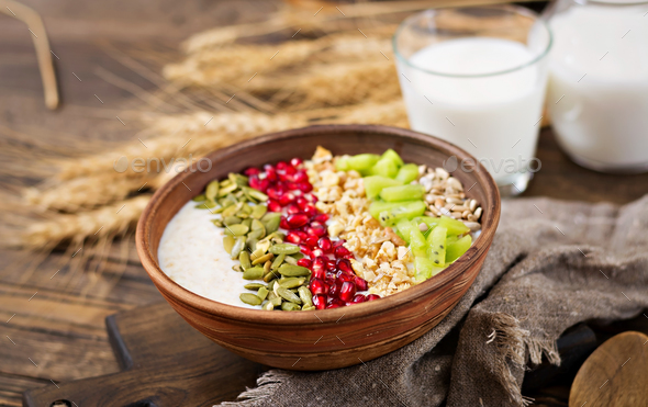 Delicious and healthy oatmeal with kiwi, pomegranate and seeds - Stock Photo - Images