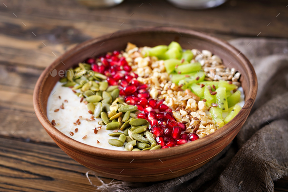 Delicious and healthy oatmeal with kiwi, pomegranate and seeds. - Stock Photo - Images