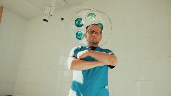 the Doctor Crosses His Arms Against the Background Surgeon Turns on Light in Hospital Room alt