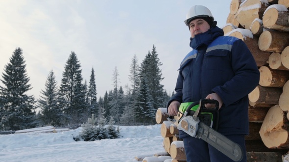 Worker With Chain Saw Against Pile of Logs