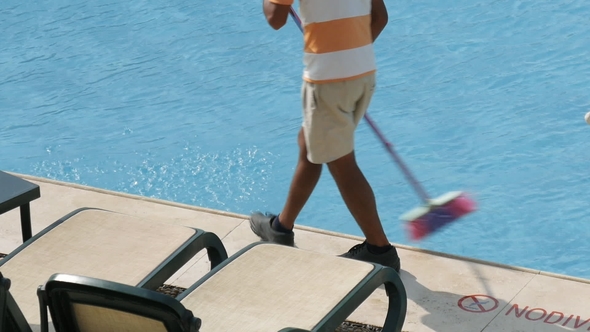 Worker Is Cleaning the Water Pool with Brush