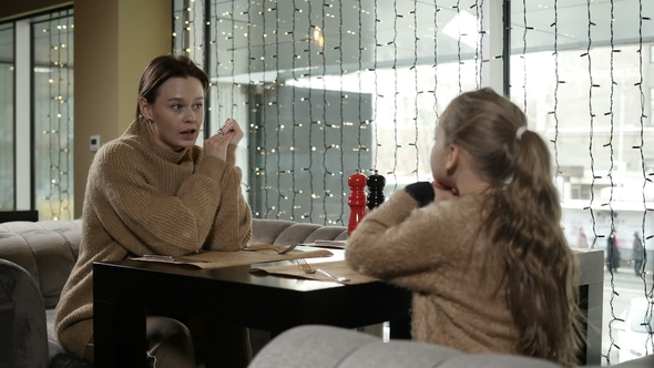 Mother and Daughter Are Talking in Cafe