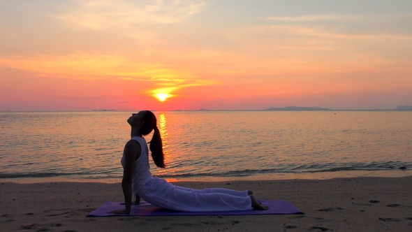 Asian Woman Practicing Yoga at the Sunset Sea