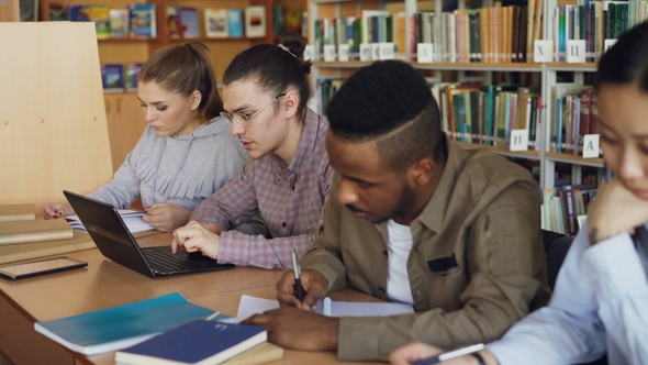 Focus on Hipster Male Student in Glasses Using Laptop Computer While Preparing for Exams alt