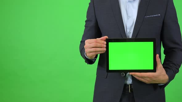 A Businessman in a Suit Holds Out a Tablet with Green Screen - Closeup - Green Screen Studio alt