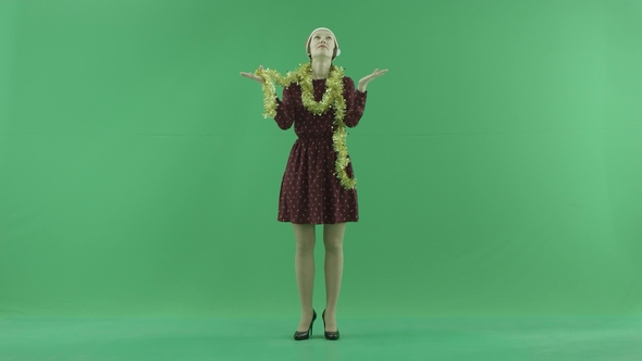A Young Christmas Woman Is Looking for a Snowfall on the Green Screen