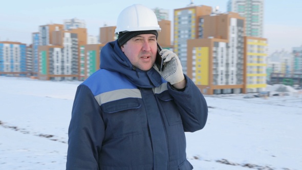 Builder Engineer at Construction Site Talking on Phone