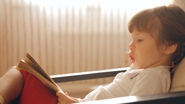 Small Girl Reading a Book in Armchair