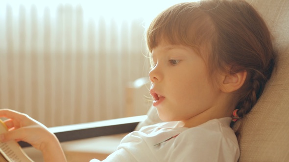 Small Girl Reading a Book in Armchair