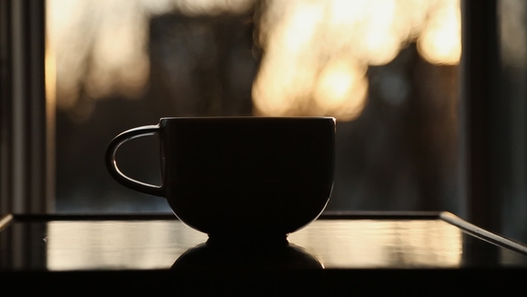 Cup of Hot Coffee or Tea at Window Side Abstract Blur Background Evening Sunset