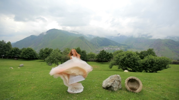 Beautiful Red-haired Bride Dancing Against the Background of Mountains