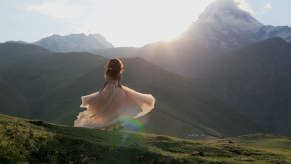Beautiful Girl in a Chic Dress Dances in the Evening Against the Backdrop of the Mountains